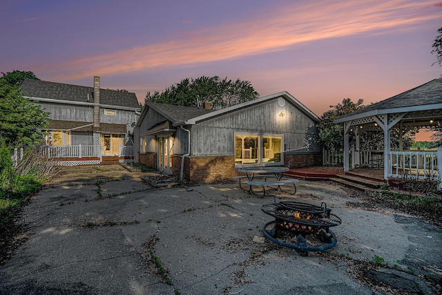 19146 Fairchild Rd, Constantine, MI 49042 - back of property at dusk with a gazebo, a fire pit, brick siding, and a wooden deck