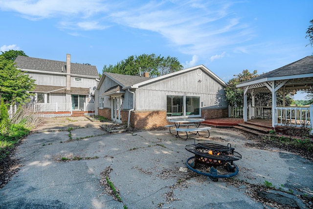 19146 Fairchild Rd, Constantine, MI 49042 - rear view of house with an outdoor fire pit, a gazebo, a deck, brick siding, and a patio area