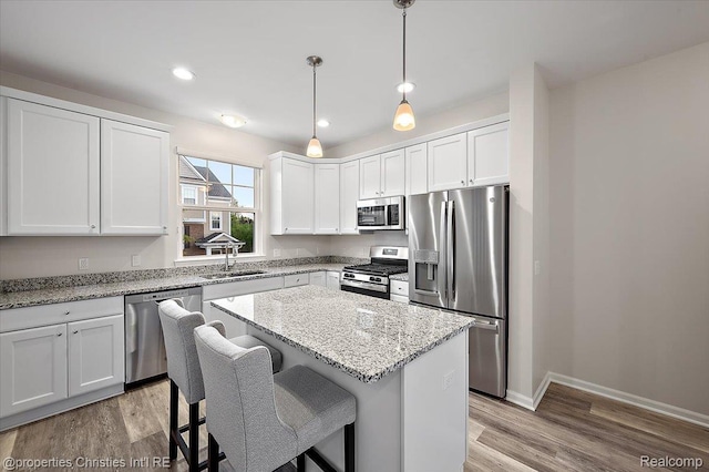 4953 Treeside Ln, Troy, MI 48098 - kitchen with stainless steel appliances, a center island, light wood-style flooring, white cabinets, and recessed lighting
