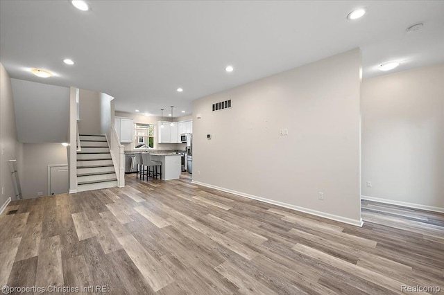 4953 Treeside Ln, Troy, MI 48098 - unfurnished living room featuring stairs, light wood finished floors, and recessed lighting