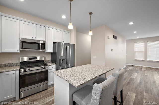 4953 Treeside Ln, Troy, MI 48098 - kitchen with appliances with stainless steel finishes, wood finished floors, light stone countertops, recessed lighting, and a kitchen island