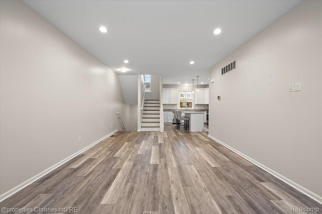 4953 Treeside Ln, Troy, MI 48098 - unfurnished living room featuring light wood-style flooring, stairs, and recessed lighting