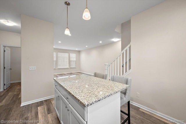 4953 Treeside Ln, Troy, MI 48098 - kitchen featuring a breakfast bar, dark wood-type flooring, pendant lighting, and light stone counters