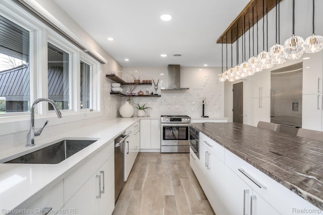 1093 Greentree Rd, Bloomfield Hills, MI 48304 - kitchen featuring stainless steel appliances, wall chimney exhaust hood, a sink, light wood-type flooring, and white cabinetry