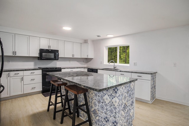 2635 E River Rd, Twin Lake, MI 49457 - kitchen with black appliances, a sink, a kitchen bar, light wood-style flooring, and recessed lighting