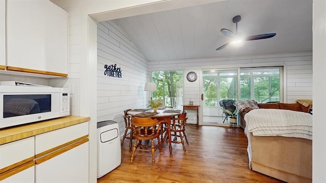 14883 Hideaway Dr, Vandalia, MI 49095 - dining space featuring lofted ceiling, healthy amount of natural light, light wood finished floors, a ceiling fan, and wood walls