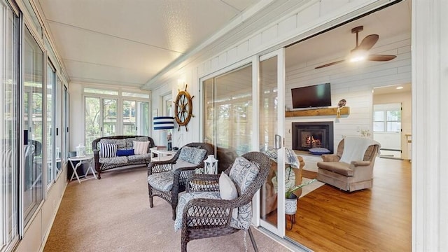 14883 Hideaway Dr, Vandalia, MI 49095 - sunroom with ceiling fan, an outdoor living space with a fireplace, crown molding, wood walls, and wood finished floors
