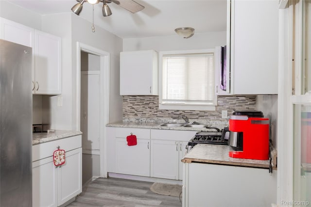 19176 Barlow St, Detroit, MI 48205 - kitchen with freestanding refrigerator, ceiling fan, backsplash, and white cabinetry