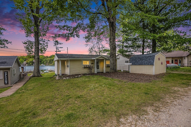 6026 Keeney Rd, Six Lakes, MI 48886 - view of front of house with a storage unit, a lawn, and a water view