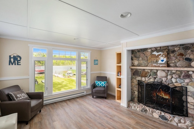 6026 Keeney Rd, Six Lakes, MI 48886 - sitting room with a baseboard heating unit, wood finished floors, a stone fireplace, and crown molding