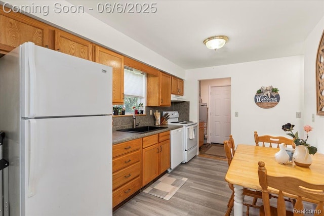 501 Front St, Holly, MI 48442 - kitchen featuring white appliances, a sink, light wood-type flooring, decorative backsplash, and under cabinet range hood