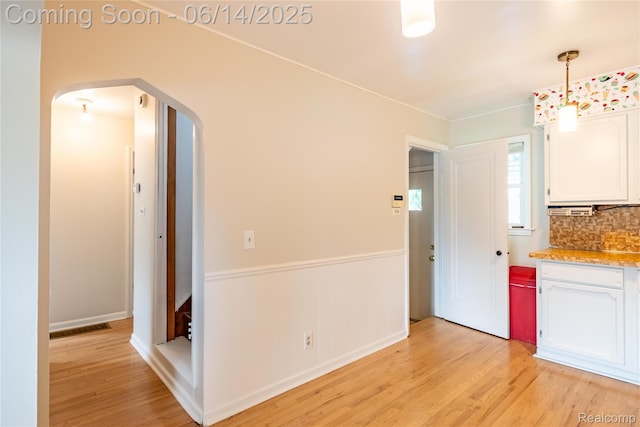 2375 Nichols Ave, Grand Blanc, MI 48507 - kitchen featuring arched walkways, white cabinetry, light wood-type flooring, backsplash, and decorative light fixtures