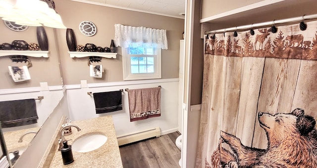 1308 Beaver Rd, Bitely, MI 49309 - full bathroom featuring a baseboard heating unit, vanity, wood finished floors, crown molding, and toilet