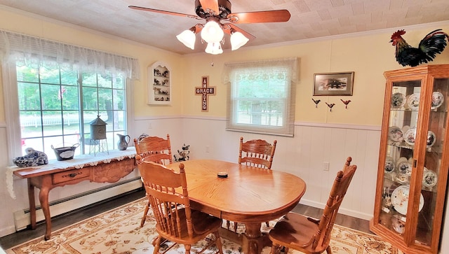1308 Beaver Rd, Bitely, MI 49309 - dining space with a baseboard heating unit, a ceiling fan, ornamental molding, light wood-style flooring, and wainscoting