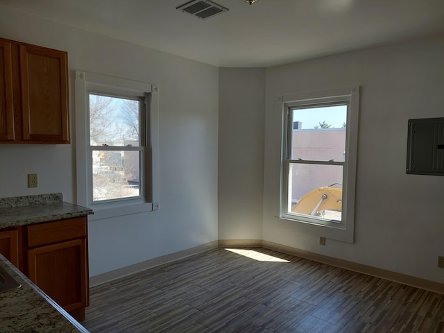 27 Rose St SW, Grand Rapids, MI 49507 - unfurnished dining area featuring electric panel, dark wood-type flooring, healthy amount of natural light, and baseboards