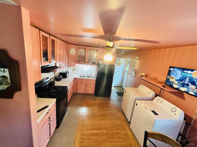 2093 California Ave, Bridgeport, MI 48601 - kitchen featuring independent washer and dryer, black appliances, under cabinet range hood, a sink, and light countertops