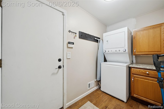 5490 Clarkston Rd, Clarkston, MI 48348 - washroom featuring estacked washer and dryer, light wood-type flooring, cabinet space, and baseboards