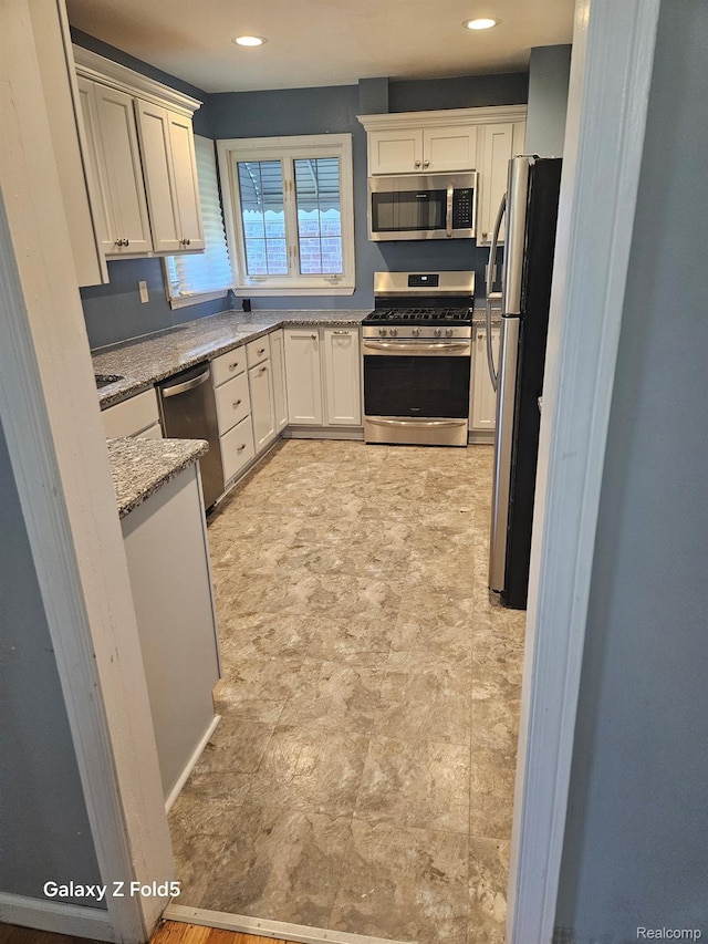 18941 Puritan St, Detroit, MI 48223 - kitchen featuring stainless steel appliances, light stone counters, white cabinetry, recessed lighting, and stone finish flooring