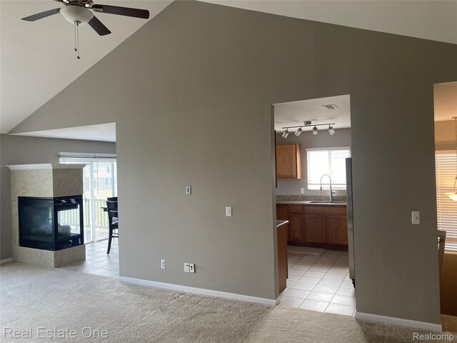 29337 Woodpark Cir Unit 60, Warren, MI 48092 - unfurnished living room featuring a ceiling fan, high vaulted ceiling, light tile patterned floors, light colored carpet, and a fireplace