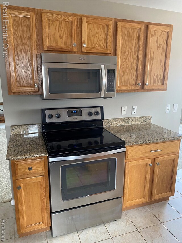 29337 Woodpark Cir Unit 60, Warren, MI 48092 - kitchen featuring stainless steel appliances, light tile patterned floors, stone counters, and brown cabinets