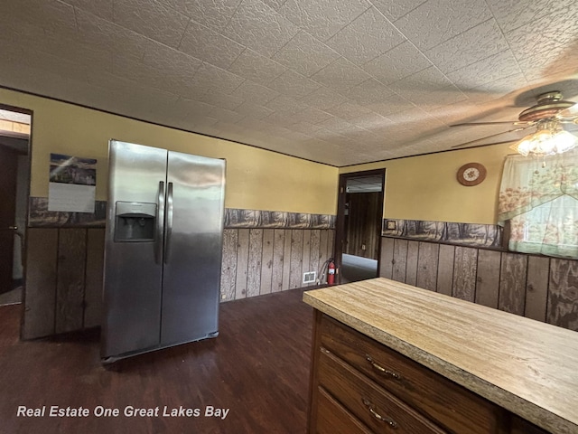 8446 Bamfield Rd, South Branch, MI 48761 - kitchen with stainless steel fridge with ice dispenser, ceiling fan, dark wood-style flooring, wainscoting, and wood walls