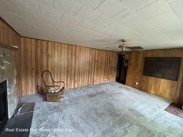 8446 Bamfield Rd, South Branch, MI 48761 - unfurnished living room with carpet flooring, wooden walls, ceiling fan, and a fireplace