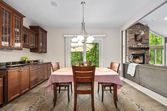 1708 N Norris Rd, Middleville, MI 49333 - dining area featuring stone tile flooring, a stone fireplace, and a chandelier