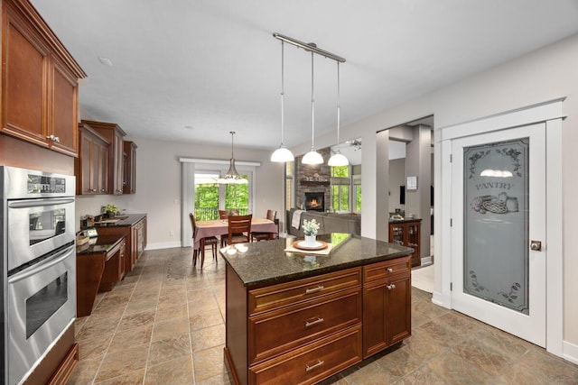 1708 N Norris Rd, Middleville, MI 49333 - kitchen featuring double oven, a stone fireplace, dark stone counters, pendant lighting, and baseboards
