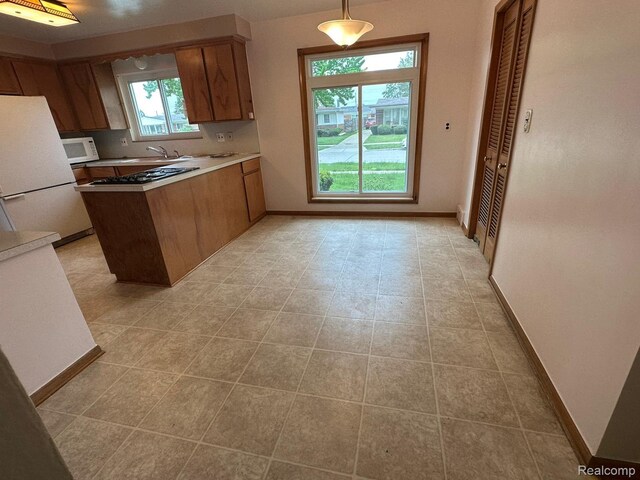 28876 Palm Beach Dr, Warren, MI 48093 - kitchen with white appliances, a peninsula, brown cabinets, baseboards, and light countertops