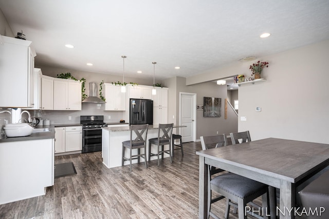 3880 Elm Ridge Dr, Holland, MI 49424 - kitchen featuring gas stove, fridge with ice dispenser, wall chimney range hood, a kitchen island, and white cabinetry