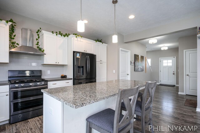 3880 Elm Ridge Dr, Holland, MI 49424 - kitchen featuring stainless steel gas range oven, refrigerator with ice dispenser, wall chimney range hood, dark wood-type flooring, and backsplash
