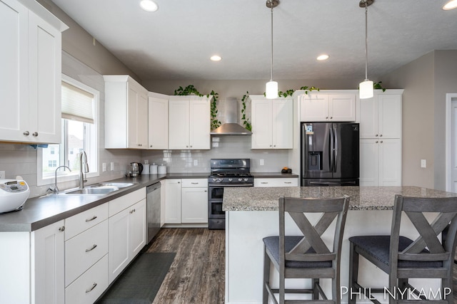 3880 Elm Ridge Dr, Holland, MI 49424 - kitchen with appliances with stainless steel finishes, wall chimney exhaust hood, a sink, dark wood finished floors, and a kitchen breakfast bar