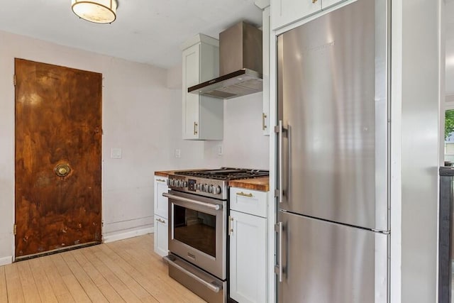 457 Gary Ave, Benton Harbor, MI 49022 - kitchen featuring wall chimney range hood, stainless steel appliances, light wood-style flooring, white cabinets, and baseboards