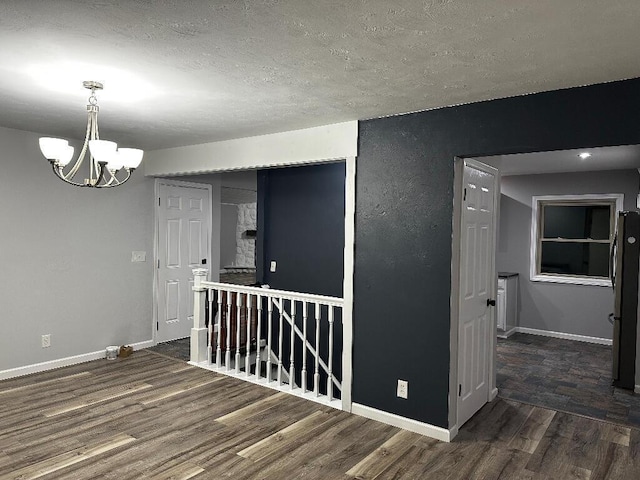 775 Riverview Dr, Plainwell, MI 49080 - empty room with a chandelier, wood finished floors, baseboards, and a textured ceiling