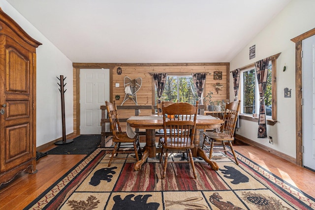 3459 N Morrie Ln, White Cloud, MI 49349 - dining room with light wood-style flooring, baseboards, wooden walls, and lofted ceiling