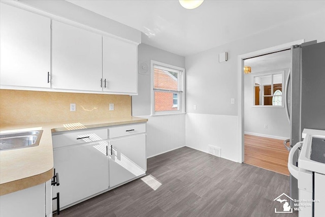 8691 Louise St, Allen Park, MI 48101 - kitchen featuring freestanding refrigerator, light countertops, dark wood finished floors, white cabinets, and wainscoting