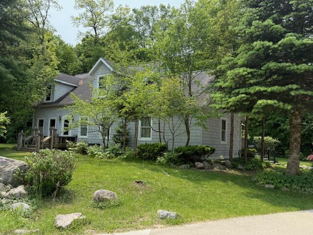 285 Scott St, Newaygo, MI 49337 - obstructed view of property featuring a front lawn, a shingled roof, and a deck