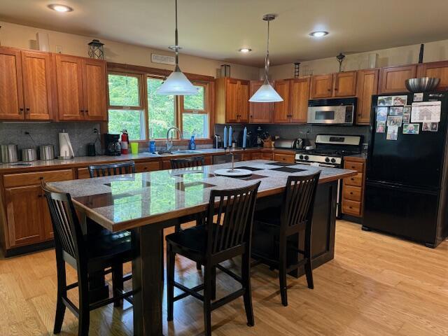 285 Scott St, Newaygo, MI 49337 - kitchen featuring stainless steel appliances, brown cabinetry, an island with sink, tasteful backsplash, and recessed lighting