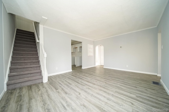 967 Keith St, Oxford, MI 48371 - unfurnished living room with arched walkways, wood finished floors, stairs, baseboards, and crown molding