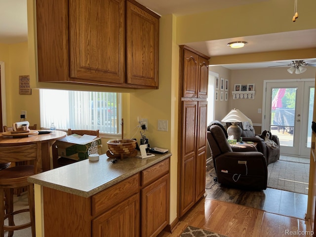 3742 W Barnes Lake Rd, Columbiaville, MI 48421 - kitchen featuring brown cabinetry, a ceiling fan, open floor plan, light wood-style flooring, and light countertops