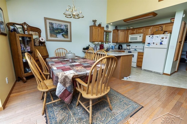 3485 Lakeshore Dr, Lupton, MI 48635 - dining area with a chandelier, light wood-type flooring, a towering ceiling, and baseboards