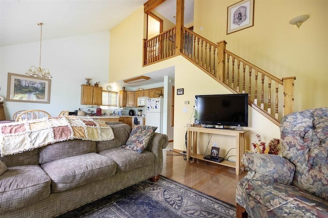 3485 Lakeshore Dr, Lupton, MI 48635 - living room featuring high vaulted ceiling, wood finished floors, a chandelier, and stairway