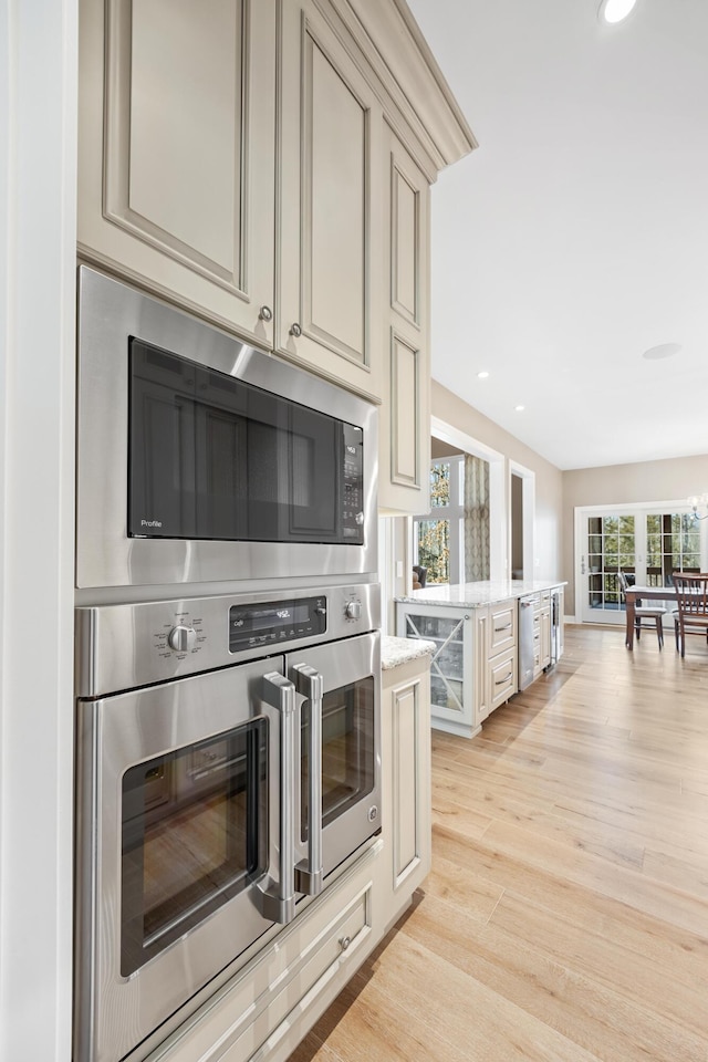 8680 Dexter Pinckney Rd, Pinckney, MI 48169 - kitchen featuring cream cabinets, stainless steel appliances, light wood-type flooring, recessed lighting, and light stone counters
