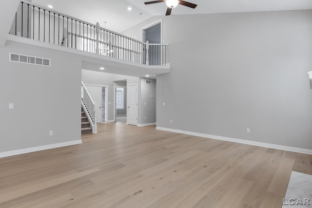 798 War Bonnet Dr, Tecumseh, MI 49286 - unfurnished living room featuring ceiling fan, stairway, light wood-type flooring, baseboards, and a high ceiling