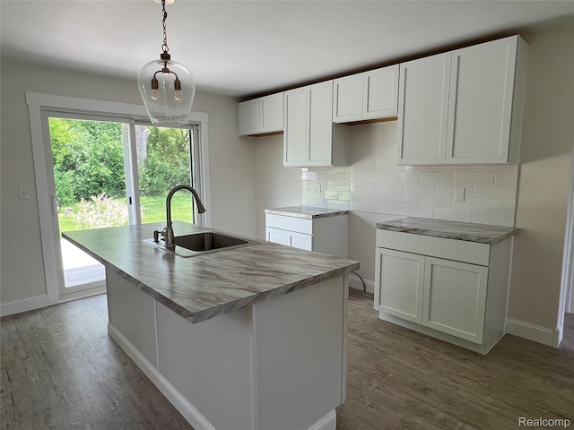 5327 E Carpenter Rd, Grand Blanc, MI 48506 - kitchen with a center island with sink, tasteful backsplash, light wood finished floors, white cabinetry, and hanging light fixtures