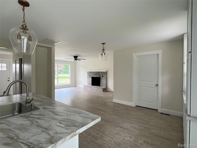 5327 E Carpenter Rd, Grand Blanc, MI 48506 - kitchen with a fireplace, a ceiling fan, wood finished floors, hanging light fixtures, and light countertops