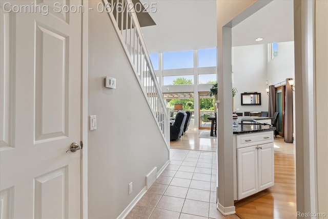 4118 Shoreview Ln, Whitmore Lake, MI 48189 - hall featuring stairs, light tile patterned flooring, baseboards, and a high ceiling