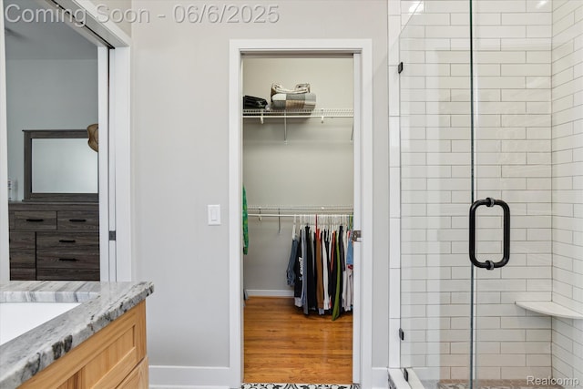 4118 Shoreview Ln, Whitmore Lake, MI 48189 - bathroom with a stall shower, vanity, baseboards, a walk in closet, and wood finished floors
