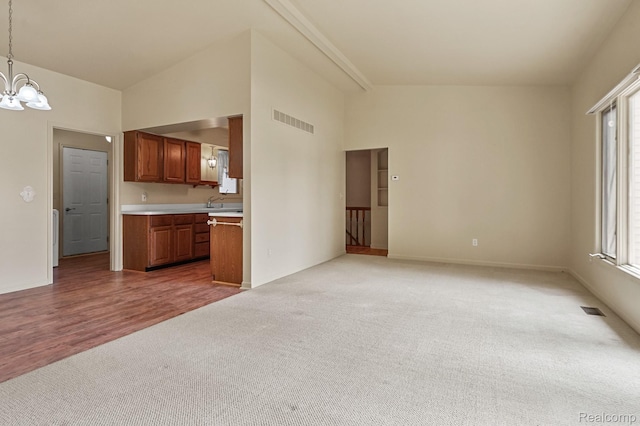 13716 Maple Grove Ave, Shelby Twp, MI 48315 - unfurnished living room featuring light colored carpet, a chandelier, lofted ceiling, plenty of natural light, and baseboards