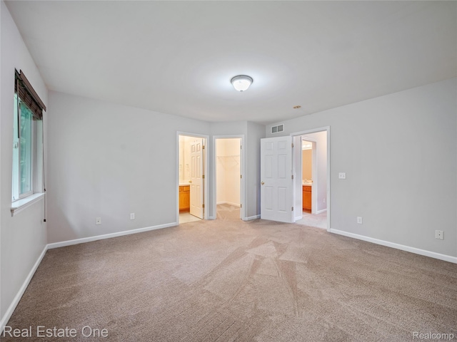 8859 Redstone Dr, Pinckney, MI 48169 - unfurnished bedroom with baseboards, a walk in closet, light colored carpet, and ensuite bathroom